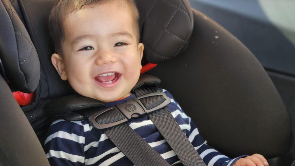 A child smiling in a carseat.